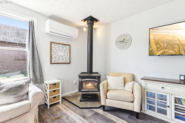 sitting room featuring a textured ceiling, a wood stove, wood finished floors, baseboards, and an AC wall unit