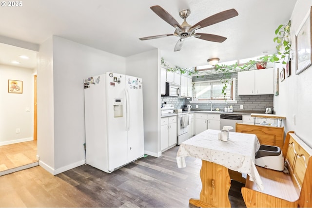 kitchen featuring a sink, decorative backsplash, white appliances, and wood finished floors