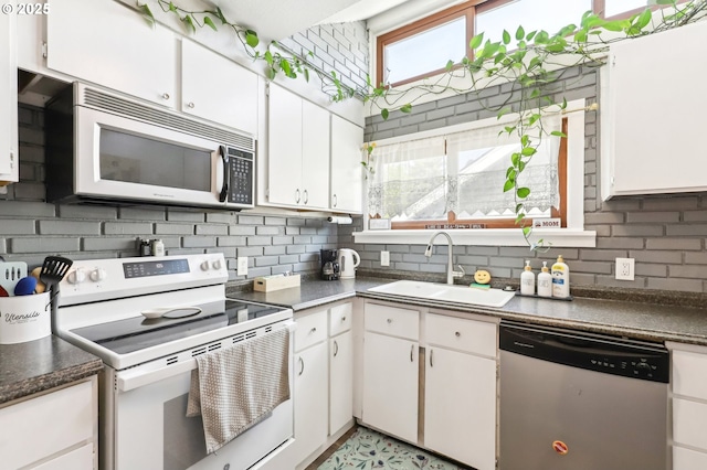 kitchen with white cabinets, appliances with stainless steel finishes, decorative backsplash, and a sink