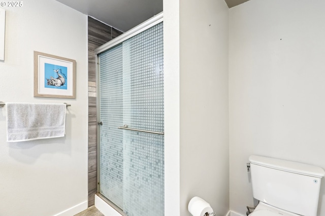 bathroom featuring baseboards, a stall shower, and toilet