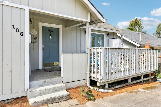 doorway to property with roof with shingles and a wooden deck