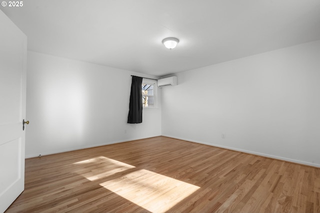 unfurnished room with a wall mounted AC and light hardwood / wood-style floors