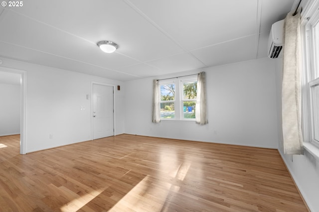 unfurnished room featuring an AC wall unit and light wood-type flooring