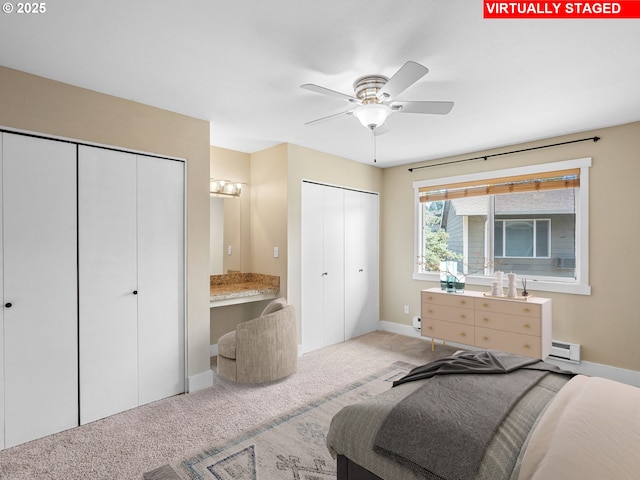 6801 SW Terri Ct Unit 60, Portland, OR 97225 - carpeted bedroom with two closets, a baseboard heating unit, and a ceiling fan
