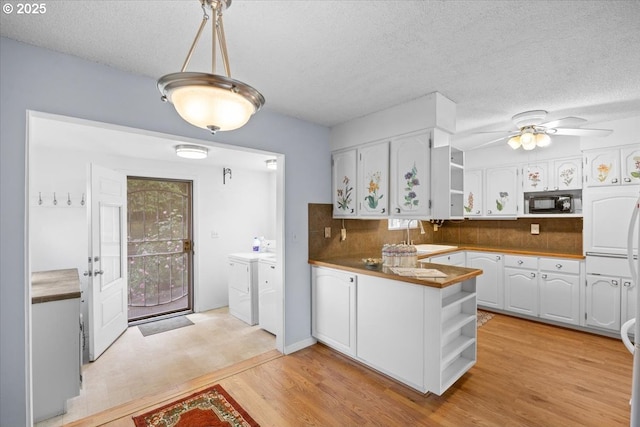 744 NE Craig St, Myrtle Creek, OR 97457 - kitchen with open shelves, separate washer and dryer, black microwave, white cabinets, and decorative backsplash