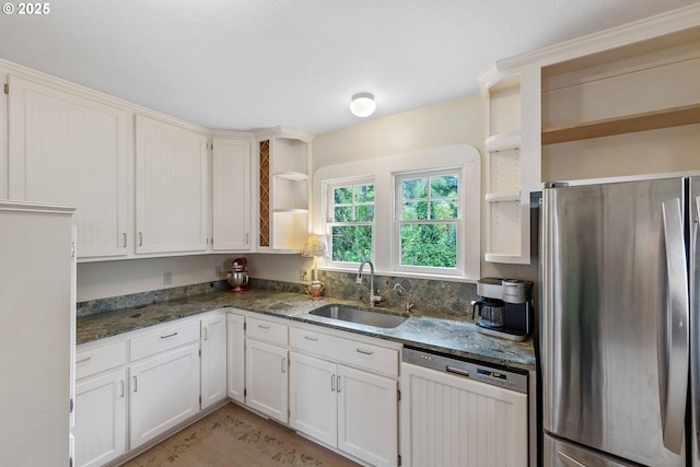 kitchen featuring open shelves, freestanding refrigerator, dishwashing machine, a sink, and dark stone countertops