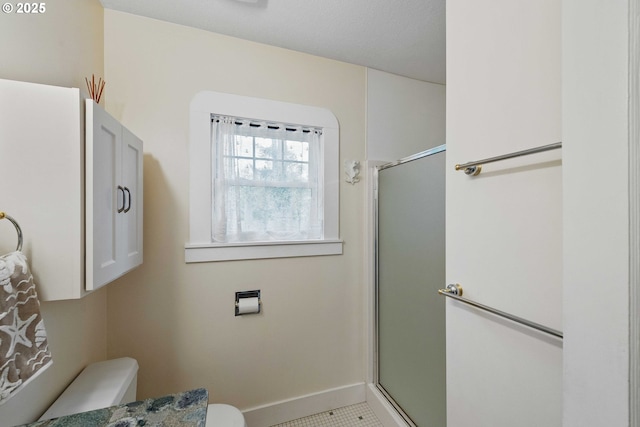 bathroom with toilet, a shower stall, and baseboards