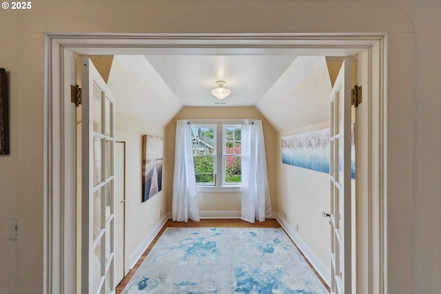 bonus room featuring vaulted ceiling, light wood-type flooring, and baseboards