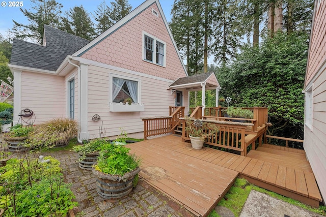 back of property featuring a shingled roof and a wooden deck
