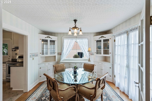 dining space featuring a chandelier, light wood-style floors, and an ornate ceiling