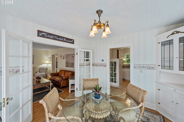 dining area with a chandelier, light wood-style floors, and french doors