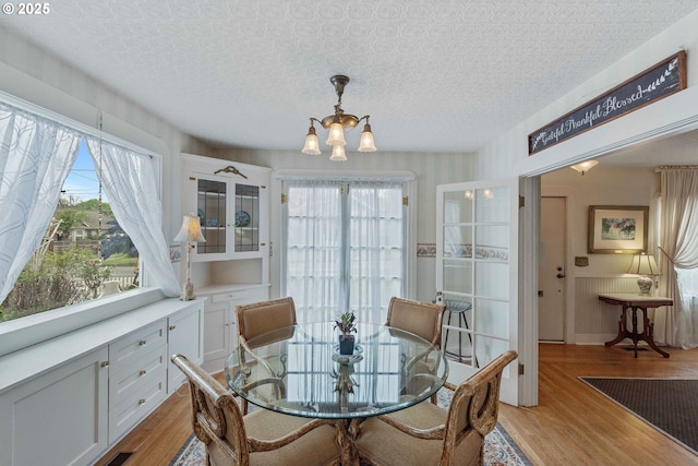dining space with a chandelier, healthy amount of natural light, and light wood-type flooring