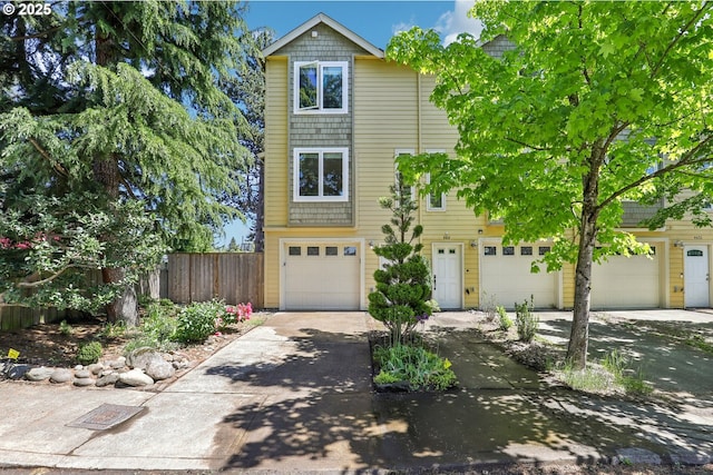 multi unit property with driveway, an attached garage, and fence
