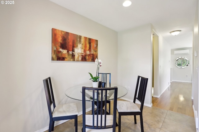 dining room with a wall mounted AC, baseboards, and light tile patterned floors