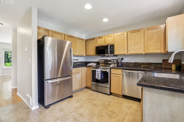 kitchen featuring stainless steel appliances, light brown cabinetry, a sink, recessed lighting, and light tile patterned floors