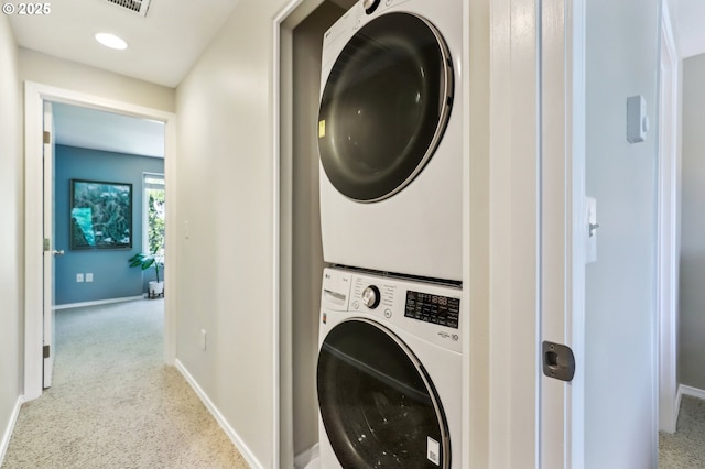 washroom featuring stacked washing machine and dryer, baseboards, and recessed lighting