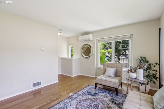 living area featuring a wall mounted air conditioner, wood finished floors, and baseboards