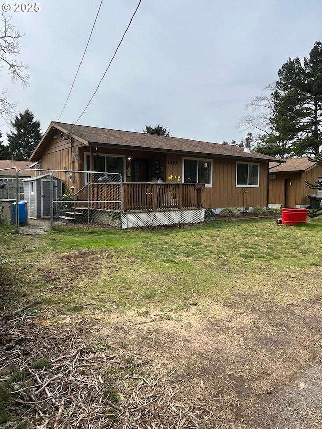 ranch-style house featuring a front yard, an outbuilding, a shed, and a wooden deck