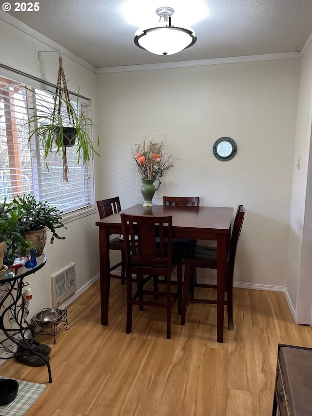 living area featuring a wall mounted AC, ornamental molding, wood finished floors, and a wood stove