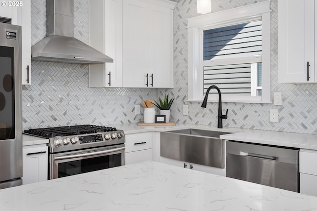3817 NE 11th Ave, Portland, OR 97212 - kitchen with wall chimney exhaust hood, appliances with stainless steel finishes, a sink, backsplash, and white cabinetry