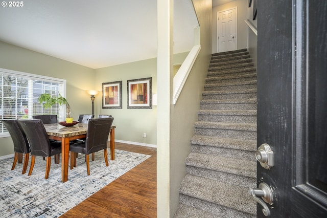 dining space featuring stairs, baseboards, and wood finished floors
