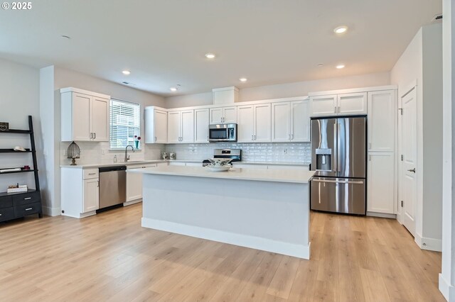 12935 SW Tabor Ter, Beaverton, OR 97007 - kitchen with appliances with stainless steel finishes, light countertops, backsplash, a kitchen island, and recessed lighting