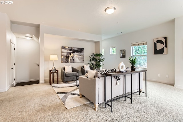 living area featuring visible vents, light colored carpet, and baseboards