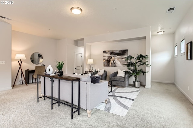 living area featuring light carpet, visible vents, and baseboards