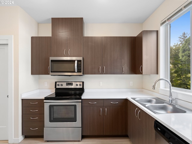 10831 E Burnside St, Portland, OR 97216 - kitchen featuring appliances with stainless steel finishes, a sink, light countertops, and dark brown cabinetry