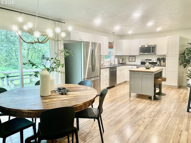 23610 E Gumjuwac Rd, Brightwood, OR 97011 - kitchen featuring stainless steel appliances, a chandelier, white cabinetry, a center island, and light wood finished floors