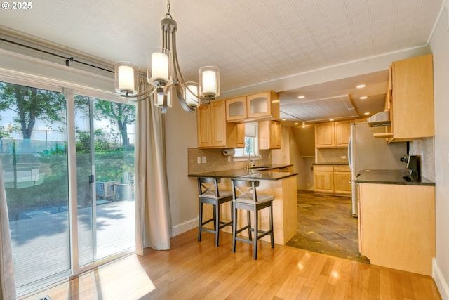 458 NW 21st St, Pendleton, OR 97801 - kitchen with dark countertops, light brown cabinetry, a peninsula, light wood finished floors, and recessed lighting