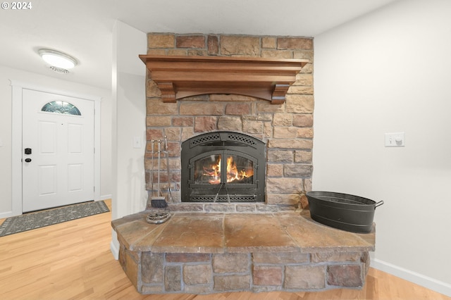 interior details with a stone fireplace, wood finished floors, and baseboards