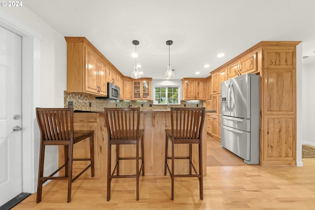 kitchen featuring appliances with stainless steel finishes, backsplash, a peninsula, and a kitchen breakfast bar