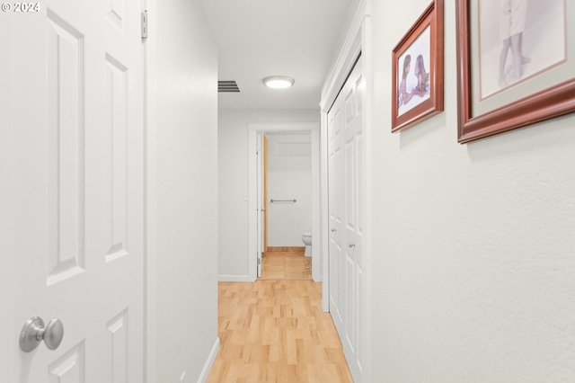 hallway with light wood finished floors, baseboards, and visible vents