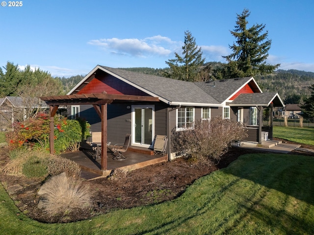 exterior space featuring a patio area, a shingled roof, a lawn, and a pergola