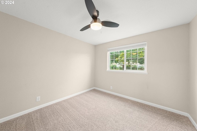 carpeted spare room featuring a ceiling fan and baseboards