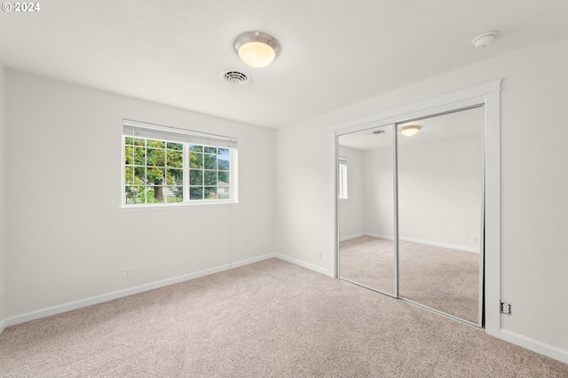 unfurnished bedroom with carpet floors, baseboards, visible vents, and a closet