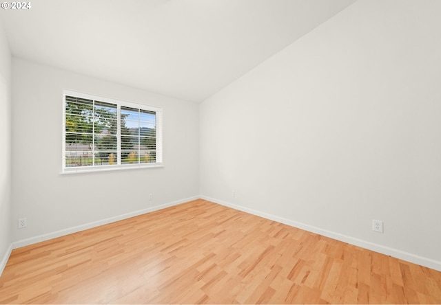 spare room featuring lofted ceiling, wood finished floors, and baseboards