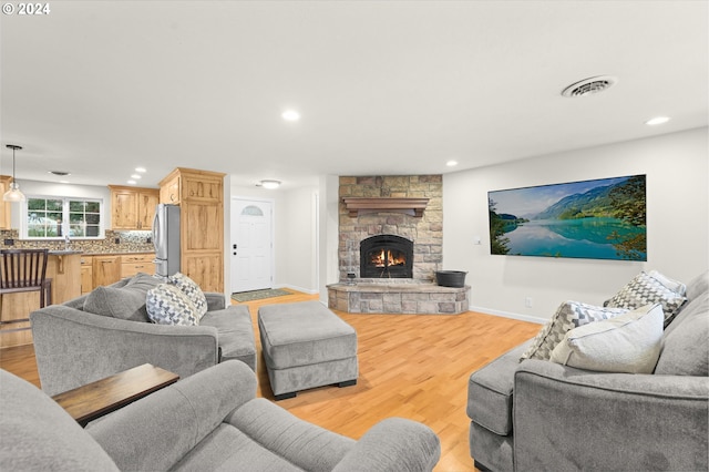 living area featuring recessed lighting, a fireplace, visible vents, baseboards, and light wood finished floors