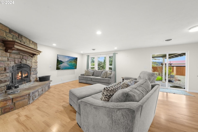 living room featuring plenty of natural light, light wood-style flooring, a fireplace, and visible vents