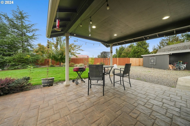 view of patio featuring an outbuilding, a shed, outdoor dining area, and a fenced backyard