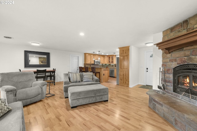 living area with light wood-style flooring, a fireplace, visible vents, and baseboards