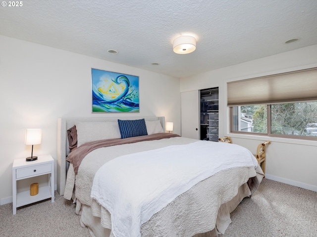 bedroom featuring a closet, light colored carpet, a textured ceiling, and baseboards