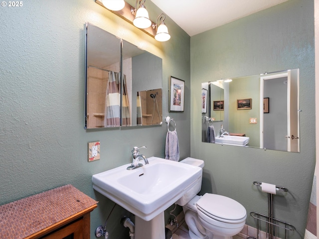 bathroom featuring a sink, curtained shower, toilet, and a textured wall