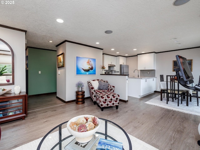 living room with a textured ceiling, wood finished floors, and crown molding