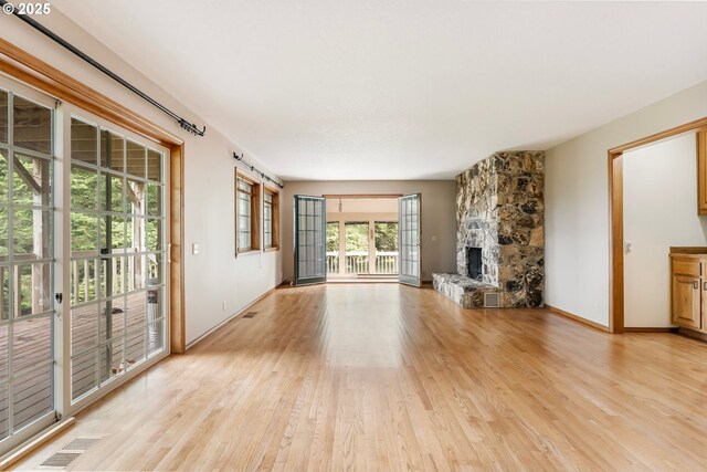 21075 NE Turner Ln, Hillsboro, OR 97123 - unfurnished living room featuring light wood-style floors, a stone fireplace, and baseboards