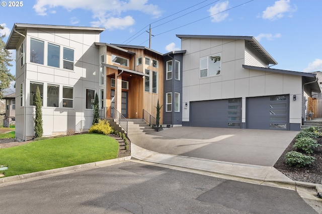 modern home with an attached garage, concrete driveway, and a front yard