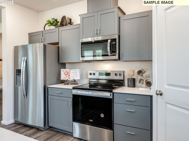 kitchen featuring gray cabinets, appliances with stainless steel finishes, light countertops, and dark wood finished floors