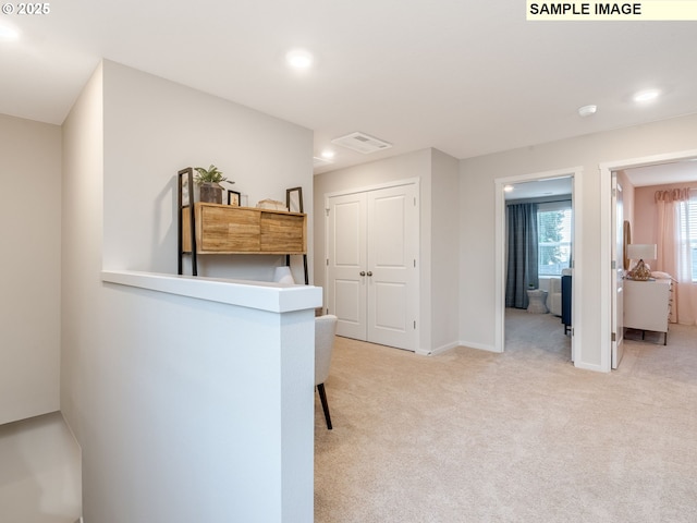 hall featuring visible vents, baseboards, recessed lighting, and light carpet