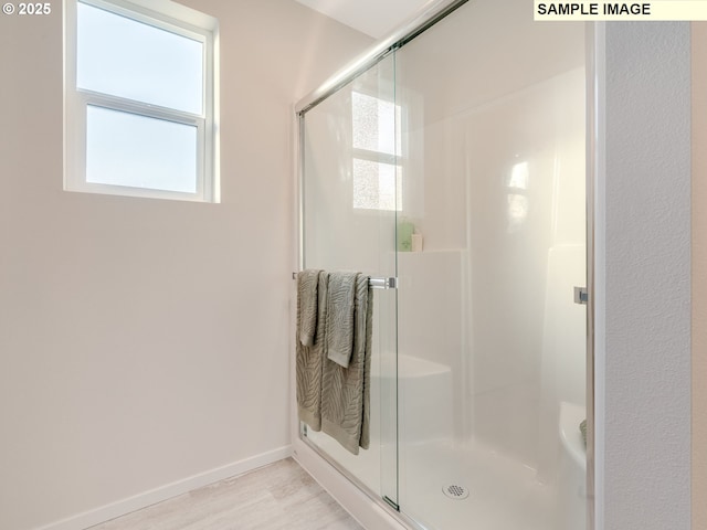 bathroom with a stall shower, wood finished floors, and baseboards